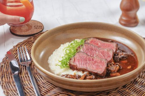 a bowl of food with meat and beans and mushrooms at Japaratinga Lounge Resort - All Inclusive in Japaratinga