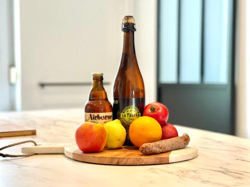 a bottle of beer and fruit on a cutting board at La Parenthèse - Peaceful and family-friendly cottage in Bastogne in Bastogne
