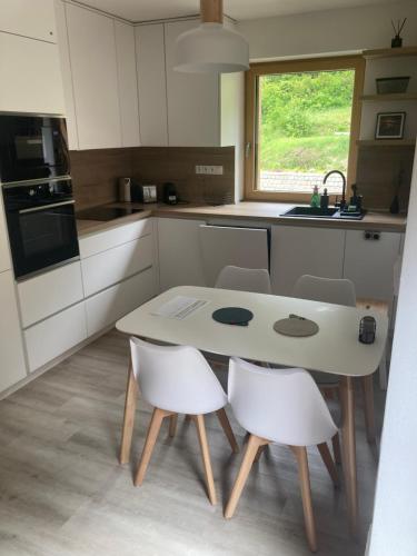 a kitchen with a table and white chairs in it at Apartmán Mariánská Hora in Albrechtice v Jizerských horách