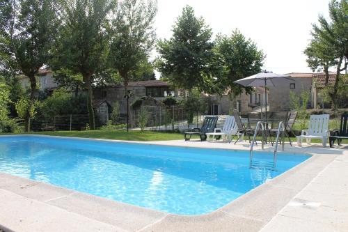 a swimming pool with a table and chairs and an umbrella at Agroturismo Quinta De Travancela in Amarante