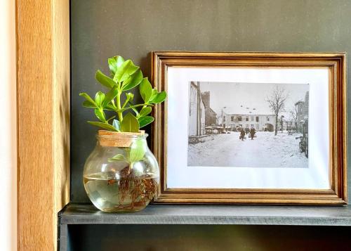 a vase sitting on a shelf next to a picture at La Parenthèse - Peaceful and family-friendly cottage in Bastogne in Bastogne