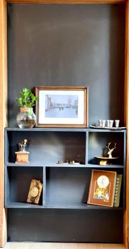 a blue book shelf with a picture and books at La Parenthèse - Peaceful and family-friendly cottage in Bastogne in Bastogne