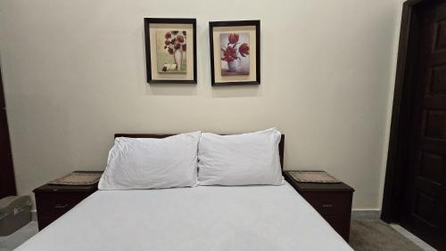 Un dormitorio con una cama con dos cuadros en la pared. en Two bedroom furnished apartment in Main Shahrah e Faisal Karachi, en Karachi