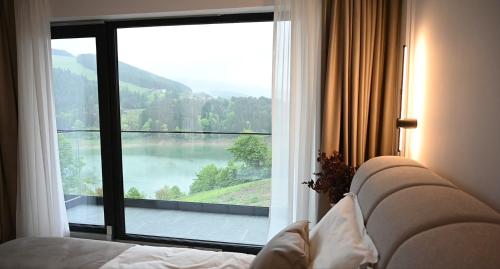 a bedroom with a large window with a view of a lake at Elira Lake in Buhalniţa