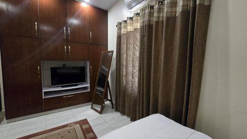 Habitación con TV, cama y cortinas. en Two bedroom furnished apartment in Main Shahrah e Faisal Karachi, en Karachi
