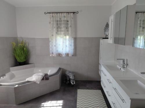 WindernにあるExklusive Ferienwohnung am Traunfallの浴槽と洗面台のある白いバスルーム