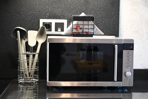 a microwave sitting on top of a counter with utensils at George's Soul in Porto Heli