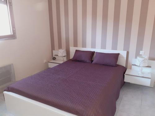 - une chambre avec un lit violet aux murs rayés dans l'établissement residence les Amaryliss, à Fréjus