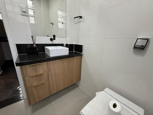 ein weißes Badezimmer mit Waschbecken und Spiegel in der Unterkunft Canal 3 lado da praia e R da Paz in Santos