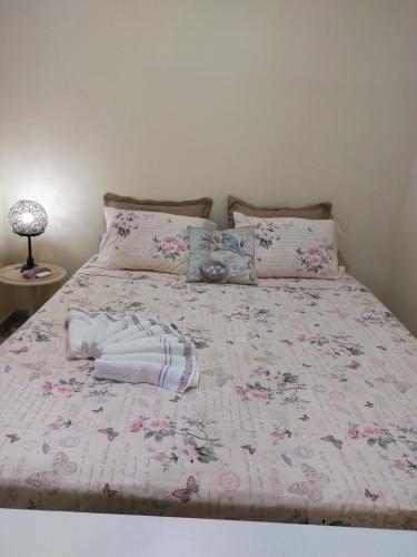 a bed with a pink bedspread with flowers on it at Paraíso nas férias in Porto Seguro