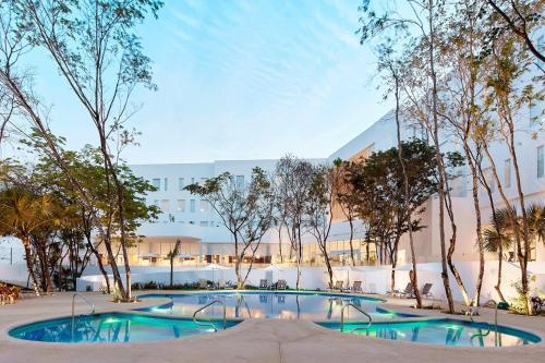 a swimming pool with trees in front of a building at Fairfield Inn & Suites by Marriott Cancun Airport in Cancún