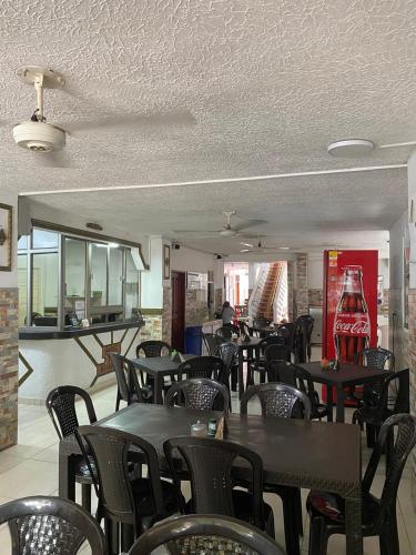 a restaurant with tables and chairs and a coke machine at HOTEL LOS GUADUALES in Barranquilla