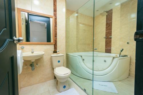 a bathroom with a toilet and a tub and a sink at Mandala Medellín Belén By GyC Hotels in Medellín