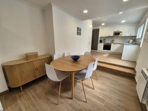 a dining room with a wooden table and white chairs at La casita de Hortensia in Nigrán