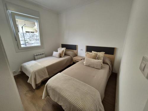 a small room with two beds and a window at La casita de Hortensia in Nigrán