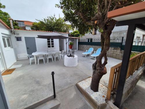 a patio with a table and chairs and a tree at La casita de Hortensia in Nigrán