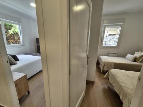 a small bedroom with two beds and a window at La casita de Hortensia in Nigrán