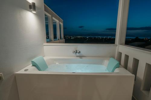 una bañera en un baño con ventana en Areti White Villas - Villa 1, en Loutraki