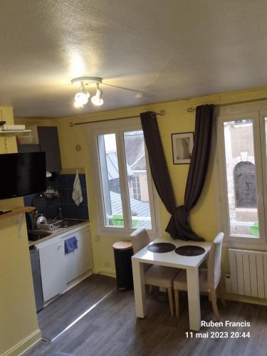 un salon avec une table et une cuisine dans l'établissement Charmant studio à 2 mn à pied de la gare de Rouen, à Rouen