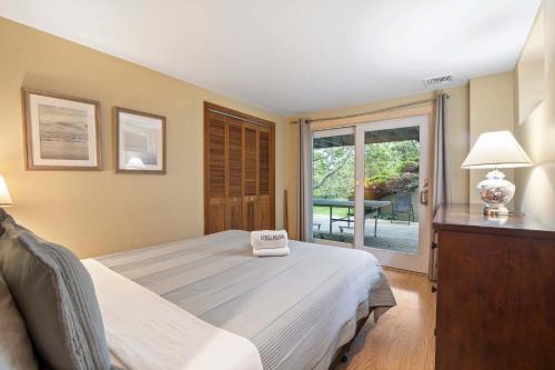 a bedroom with a bed and a sliding glass door at Walk to Beach w Roof-Level Deck in Truro