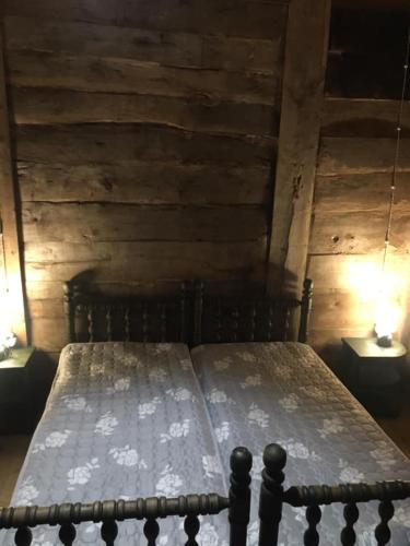 a bed in a wooden room with two lamps at Thea's Ethnographic Guest House in Nap'ich'khovo