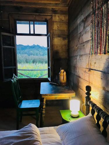 a bedroom with a bed and a table and a window at Thea's Ethnographic Guest House in Nap'ich'khovo