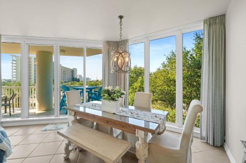 a dining room with a table and chairs and windows at Silver Shells in Destin
