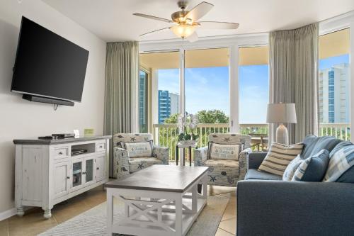 a living room with a tv and a couch and chairs at Silver Shells in Destin