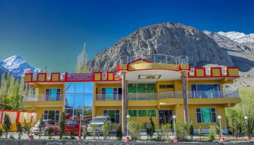 锡卡都Skardu view point hotel and huts的一座黄色的建筑,背景是一座山