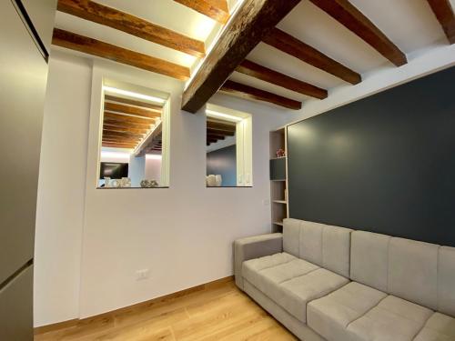 a living room with a couch and two windows at Zenone monolocale Reggio Emilia Historic Center in Reggio Emilia