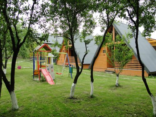 a park with a playground with trees and a house at Casuta Pescarului in Şimnicu de Sus