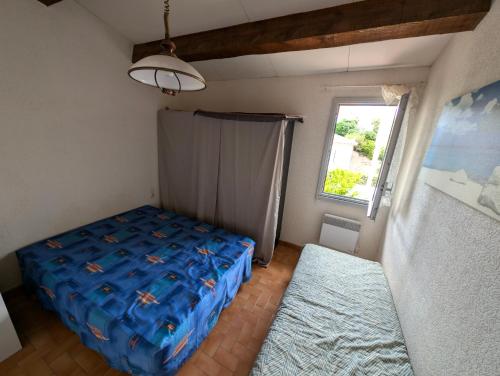 une chambre avec un lit bleu et une fenêtre dans l'établissement Maison de Vacances Les Caounils à St-Pierre-La-Mer, à Fleury
