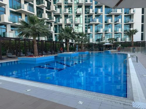 a large blue swimming pool in front of a building at Cozy studio Pet Friendly Pool, Gym, Water Near Downtown in Dubai