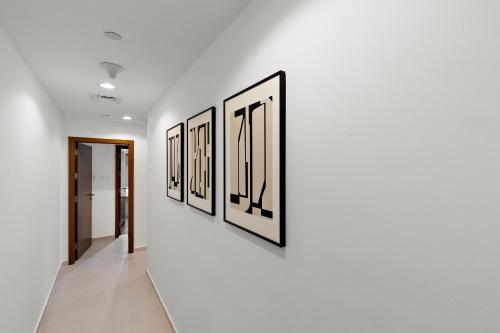 a hallway with a row of framed pictures on a wall at Desert Key - Platinum Apartments in Gate Tower, Al Reem Island in Abu Dhabi