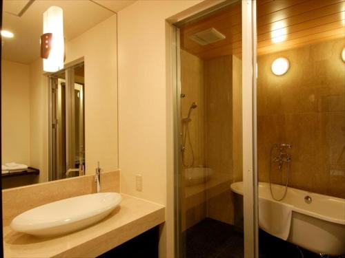 ein Badezimmer mit einem Waschbecken, einem WC und einer Badewanne in der Unterkunft Cypress Resort Kumejima in Kumejima