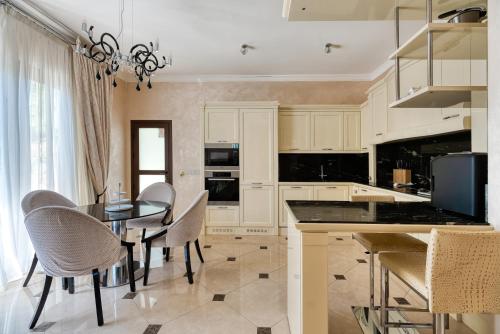 a kitchen with white cabinets and a table and chairs at Argaka Luxury Residence in Paphos City