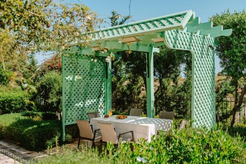 a table and chairs under a green pergola at Argaka Luxury Residence in Paphos City