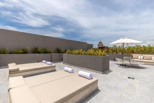 a patio with two couches and an umbrella at Best Location in Cabo Marina Private Rooftop Sleeps 8 in Cabo San Lucas