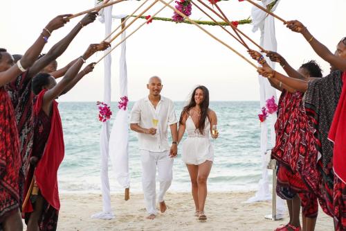 a bride and groom walking down the aisle at their wedding on the beach at Ycona Eco-Luxury Resort, Zanzibar in Dikoni