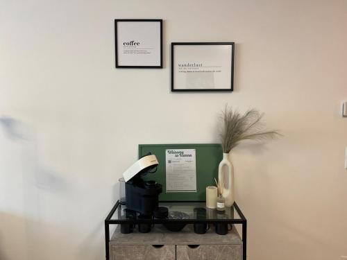 a table with a coffee maker and three pictures on the wall at Feel-good oasis with terrace in Vienna