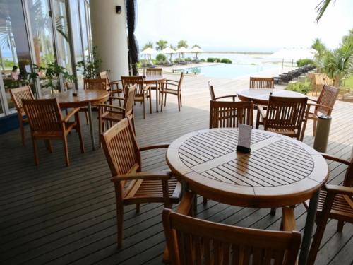 a restaurant with tables and chairs on a deck at Cypress Resort Kumejima in Kumejima