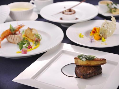 a table with white plates of food on it at Cypress Resort Kumejima in Kumejima