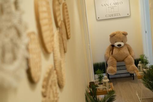 a teddy bear sitting on a bench in a room at San Carlo Apartments B&B Caserta in Caserta