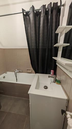 La salle de bains est pourvue d'un rideau de douche noir et d'un lavabo. dans l'établissement Joli appartement Parc Chambrun, à Nice