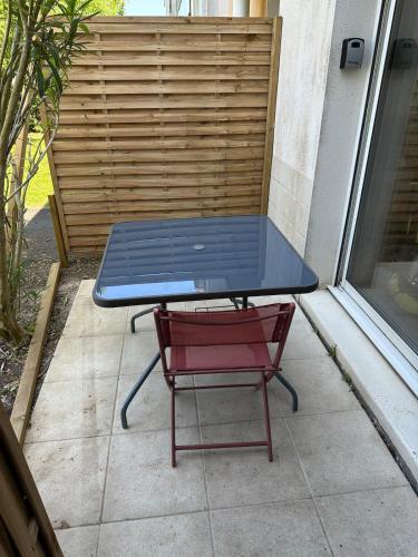 une table de pique-nique et une chaise rouge sur une terrasse dans l'établissement Appartement avec terrasse, à Aytré