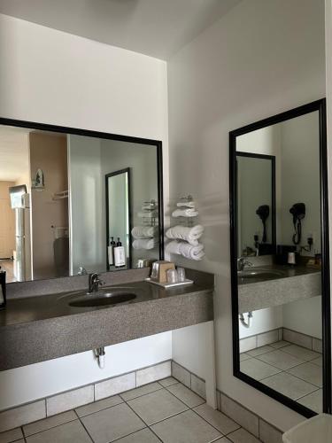 a hotel bathroom with two sinks and two mirrors at Security Inn and Suites in Lake City