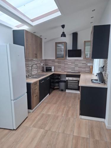 une grande cuisine avec un réfrigérateur blanc et du parquet dans l'établissement Au Bord de L'Eau, à Trith-Saint-Léger