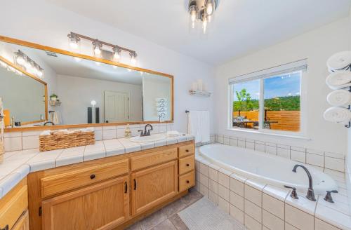 un bagno con vasca e un grande specchio di Hidden Falls Retreat Peaceful Guesthouse Near Yosemite a Oakhurst