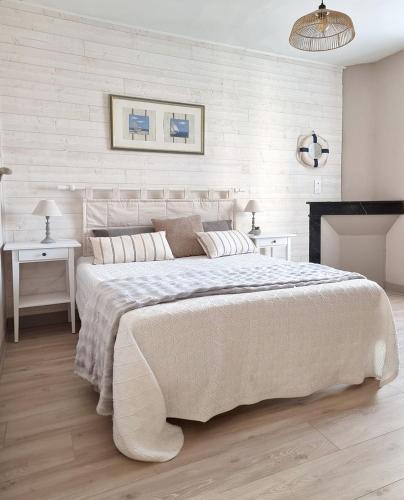 - une chambre blanche avec un grand lit et une cheminée dans l'établissement KerMady, maison proche de la mer, à Saint-Malo