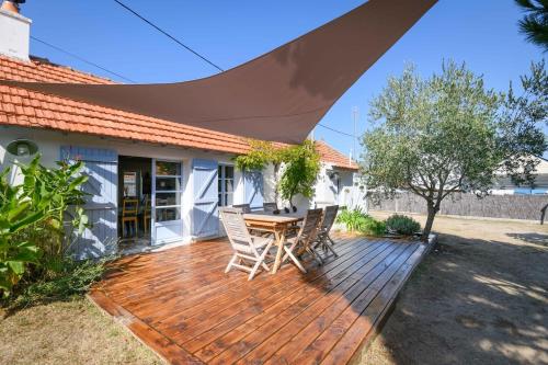 une terrasse en bois avec une table et des chaises dessus dans l'établissement Charmante maison vendéenne proche de la plage, à Notre-Dame-de-Monts